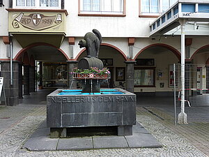 Brunnenanlage mit einer Skulptur einer Katze, die auf einem Weinfass steht, auf dem Marktplatz in Zell.