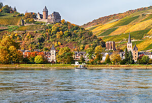 Der Fluss Rhein mit dem Stadtbild von Bacharach vor Steilhängen mit Weinreben.