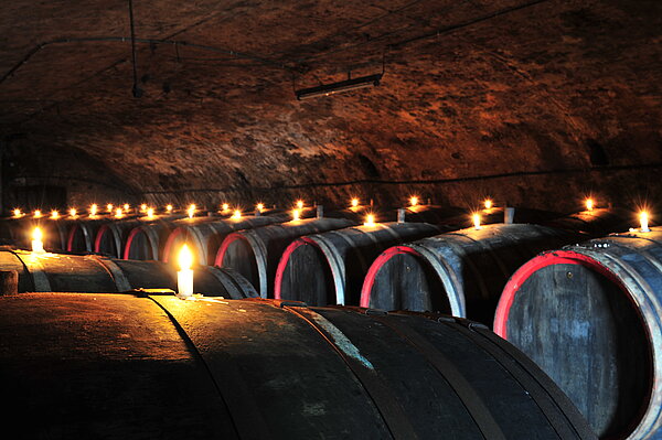 Weinfässer in einem Keller, die mit Kerzen dekoriert sind